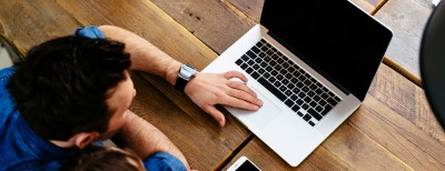 a person using a laptop computer sitting on top of a wooden table