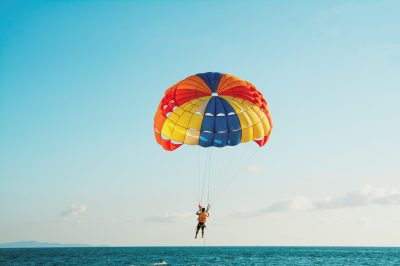 a man flying through the air while holding a colorful kite